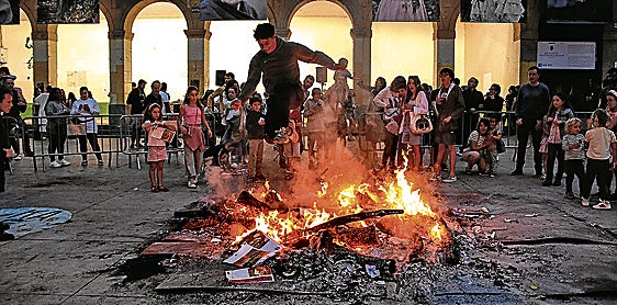 Un joven salta encima del fuego en la hoguera de San Juan de la plaza de San Nicolás de Algorta.