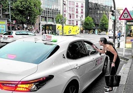 Una mujer dialoga con un taxista, junto a la Plaza Circular.