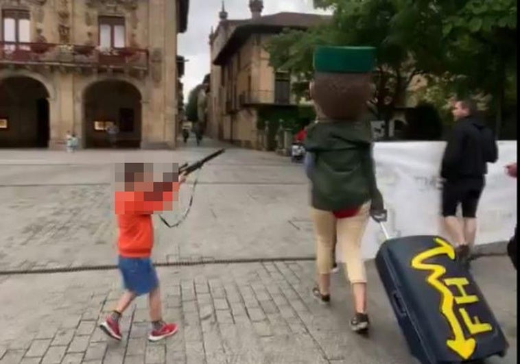 Un niño apunta con una falsa escopeta a un cabezudo vestido de guardia civil en Oñati