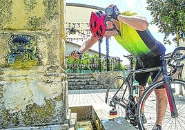 Josu Míguez se refresca en una fuente del pueblo mientras descansa de su ruta en bicicleta.