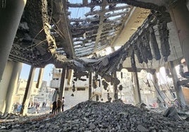 Los palestinos observan los destrozos causados por una bomba en un edificio en el norte de Gaza.