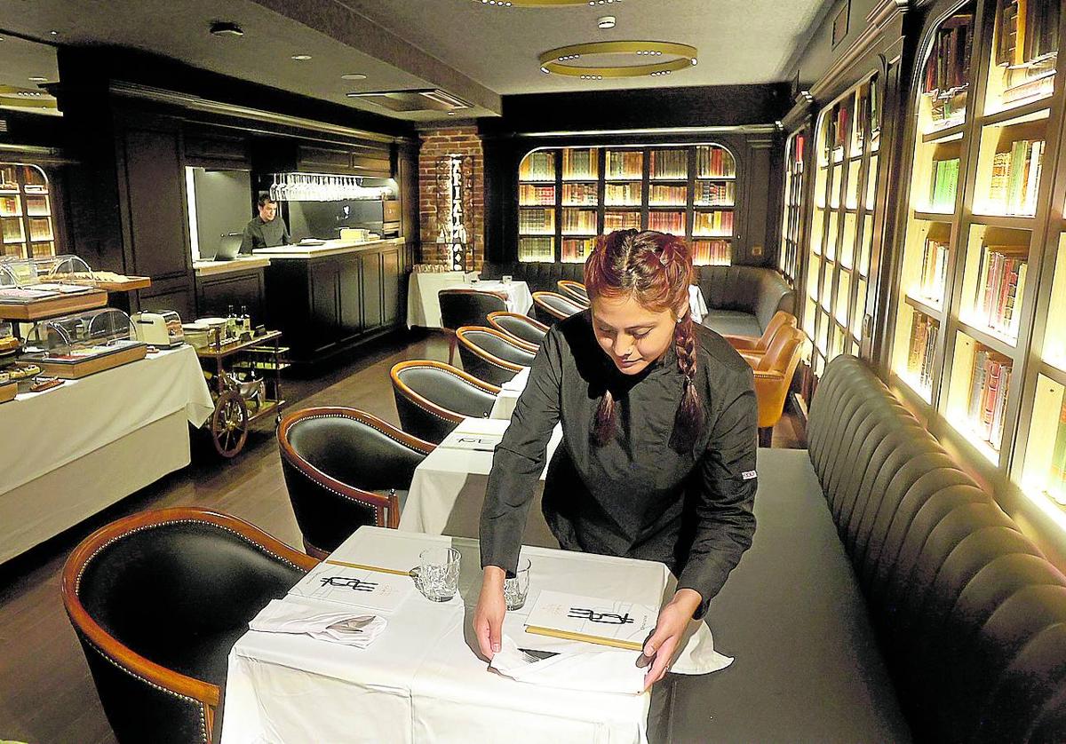 Una empleada prepara una mesa de la cafetería, que reproduce el estilo de las viejas bibliotecas inglesas.