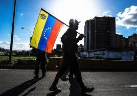 Una persona porta la bandera de Venezuela en las calles del país.