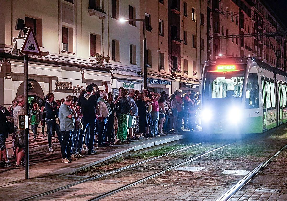 Usuarios del tranvía esperan la llegada del convoy durante una noche de fiestas de Vitoria.