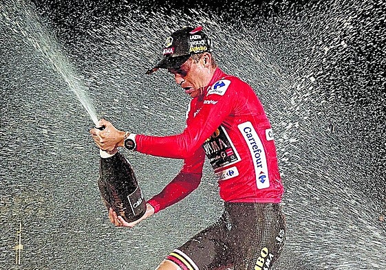 Sepp Kuss descorcha la botella de cava en el podio como campeón de la Vuelta 2023.