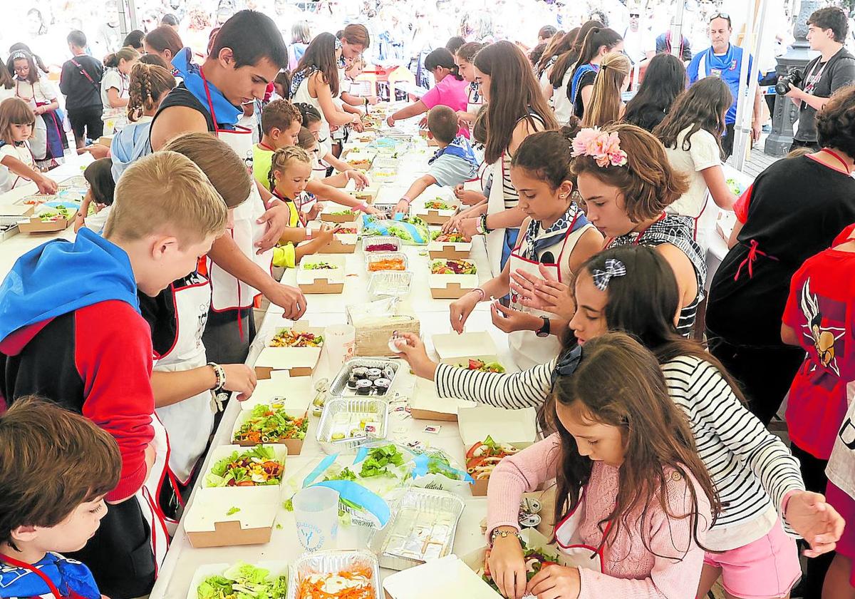 Un nutrido grupo de niños prepara ensaladas, dando rienda suelta a su creatividad desbordante.