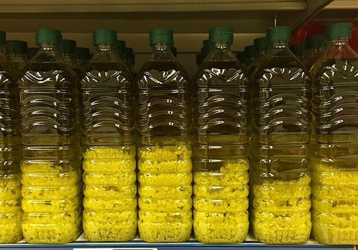 Botellas de aceite con grumos blancos en la estantería de un supermercado.