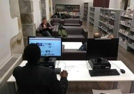 Varios vecinos leen unas publicaciones en el interior de la biblioteca