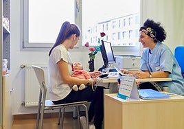 Un bebé, con su madre, en la consulta de la pediatra.