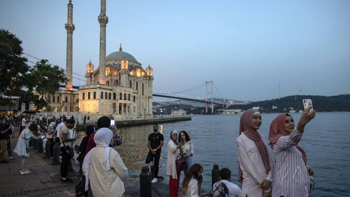 Turistas se fotografían ante la mezquita de Ortaköy y puente del Bósforo.