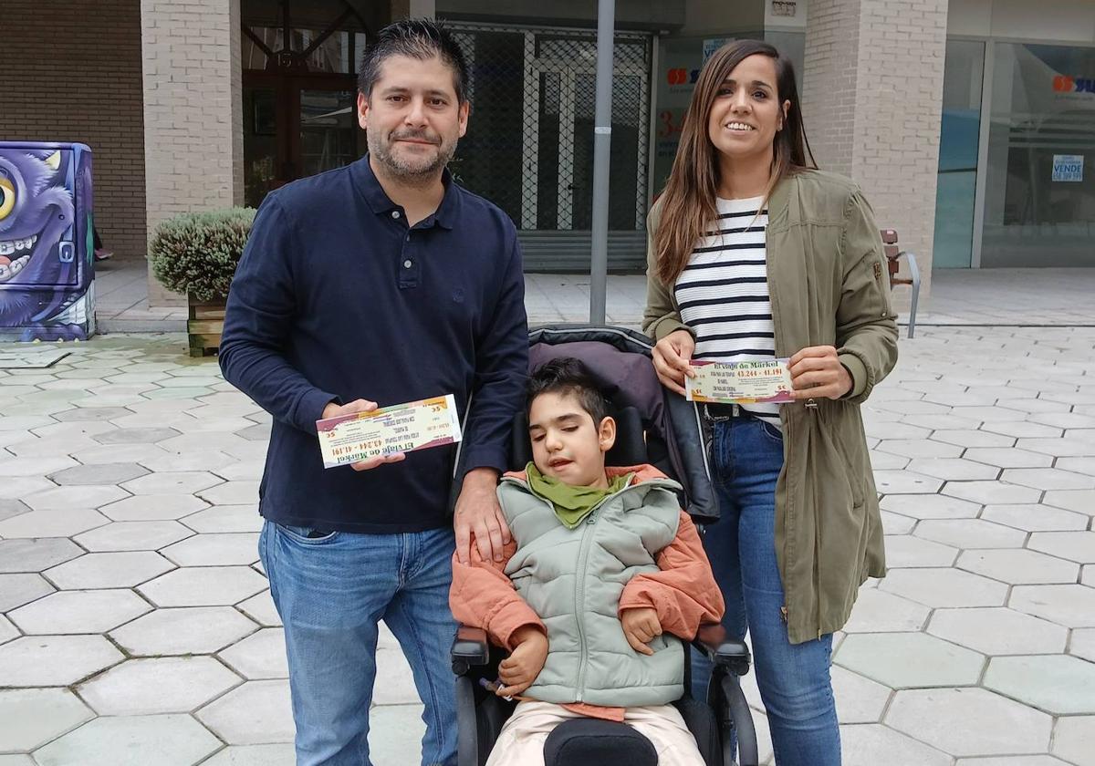 Iris Infante e Iván Corredor muestran las participaciones de la lotería de Navidad junto al pequeño Markel, de 10 años.