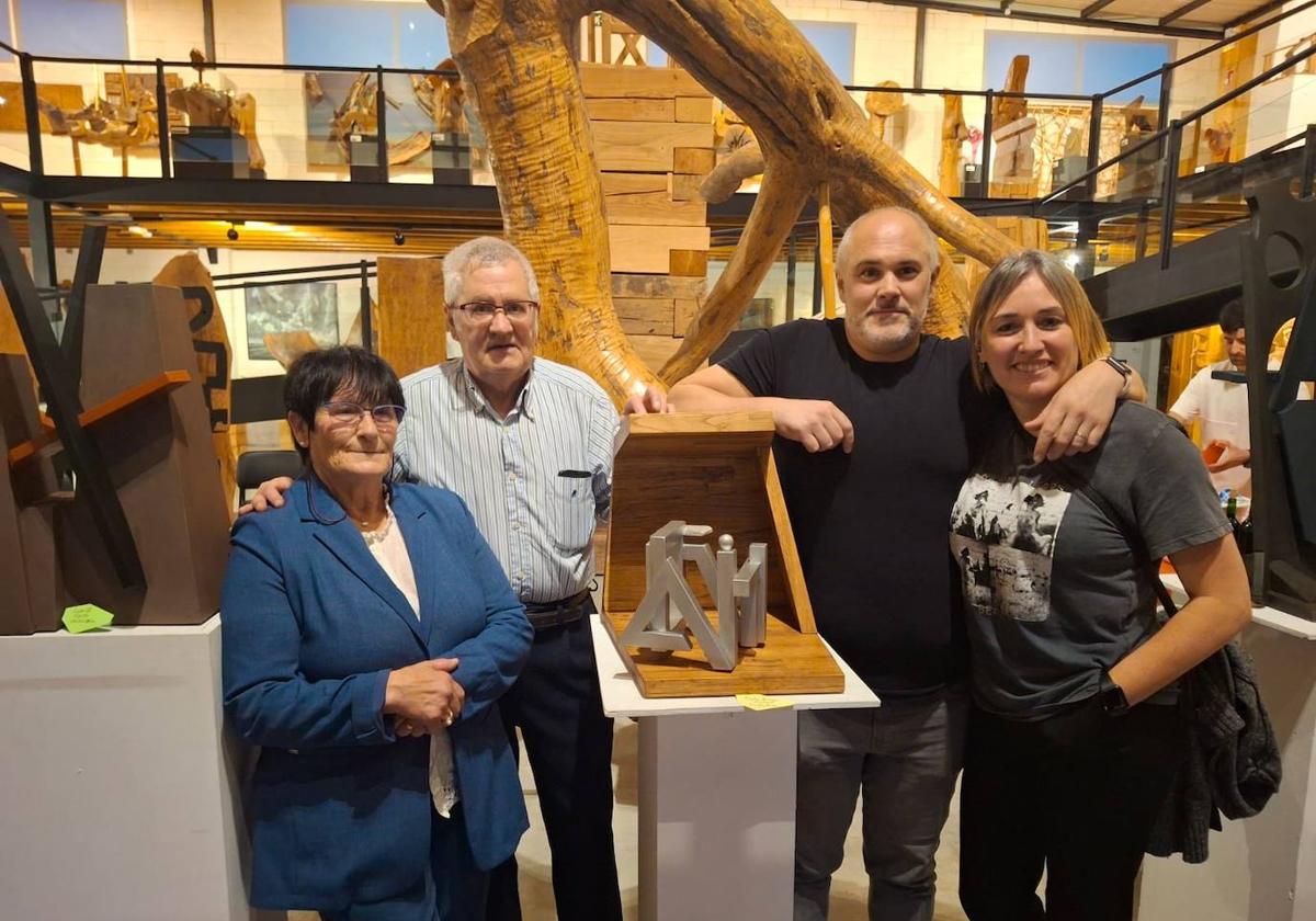 Esteban Kerexeta, con camisa a rayas, junto a una de sus obras, y varios visitantes a la exposición.