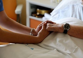 Una mujer toma la mano de su madre en una unidad de Cuidados Paliativos de Euskadi.