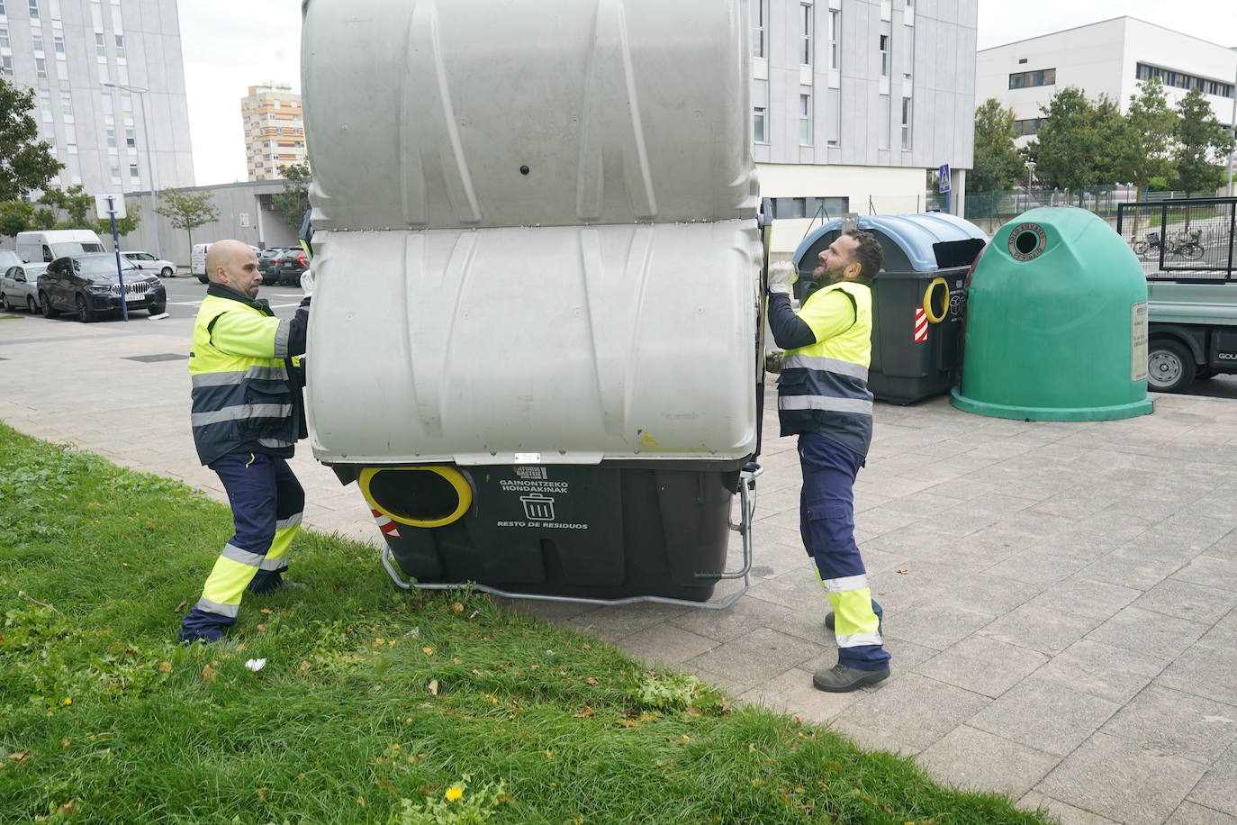 Dos operarios colocan un contenedor desplazado por el viento.