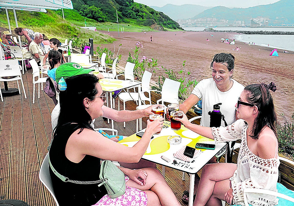 Un grupo de chavales toman un refresco en el local hostelero que está en la playa de Arrigunaga en Getxo.