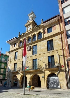 Un cicloturista se detiene frente al Ayuntamiento de Bermeo para leer uns placa conmemorativa.