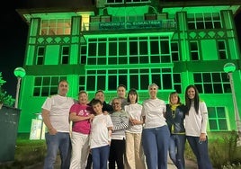 La familia de June, en el centro, posa ante la casa de cultura de Muskiz, iluminada de verde por el día mundial del síndrome de Phelan McDermid.