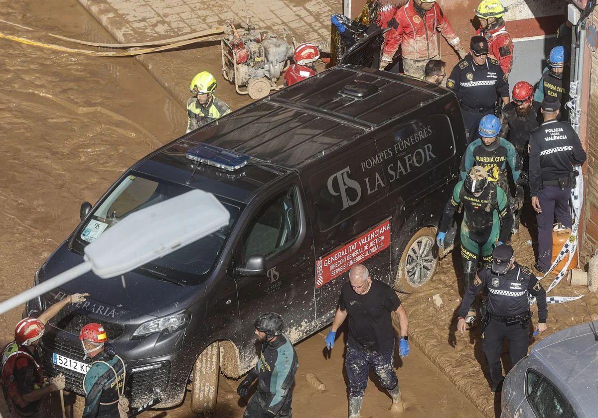 Un furgón de la funeraria sale de un garaje de La Torre con cadáveres localizados.