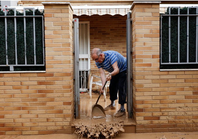 Un vecino limpia su vivienda en Picanya.