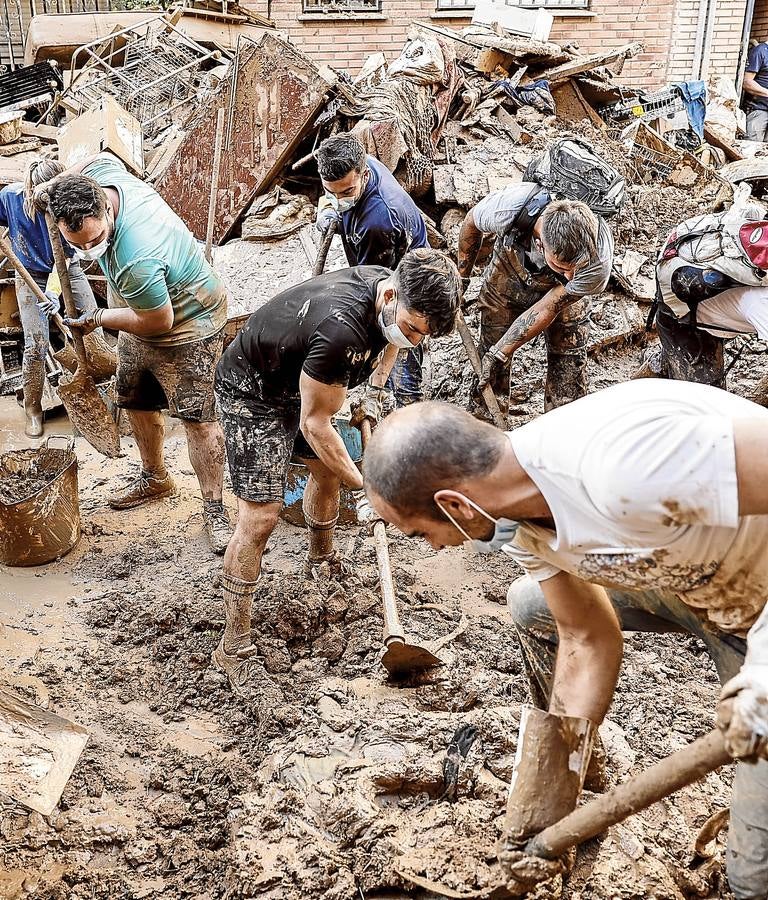Imagen - Incansables. Varias personas retiran el lodo acumulado en una calle de la localidad valenciana de Paiporta.