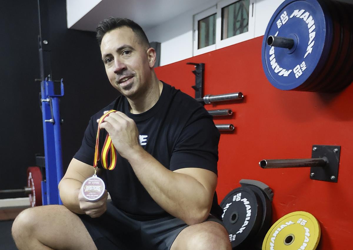 Imagen secundaria 1 - Jorge se prepara para hacer sentadillas. En la siguiente foto, con la medalla conseguida en el campeonato de España. En la última imagen, junto a una de las enormes cadenas con las que trabaja.