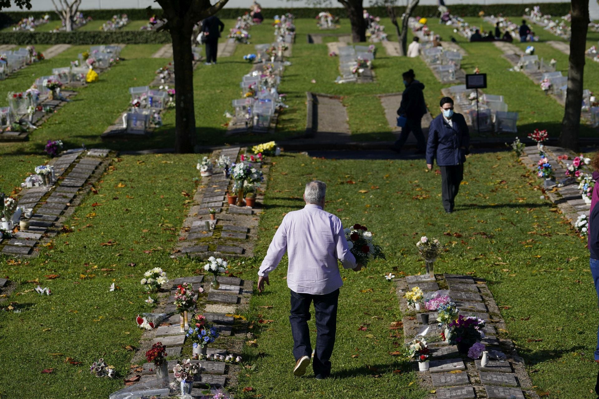 Un hombre se dispone a depositar un ramo de flores en el cementerio de Derio.
