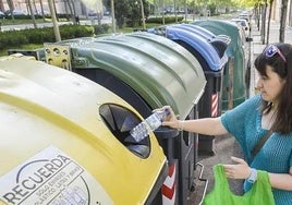 Una ciudadana recicla envases de plástico en el contenedor amarillo.