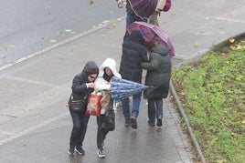 Varias personas se protegen del viento y la lluvia este sábado en Bilbao.