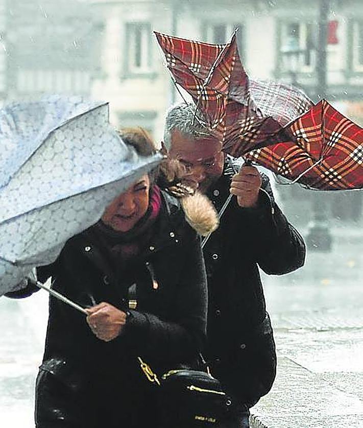 Imagen secundaria 2 - Arriba, la arena de la playa de Ereaga cubrió el paseo y la carretera que discurren en paralelo al arenal. Abajo a la izquierda, nieve en el puerto de Herrera. Y a la derecha, el viento y la lluvia volvieron ayer a ser protagonistas. 