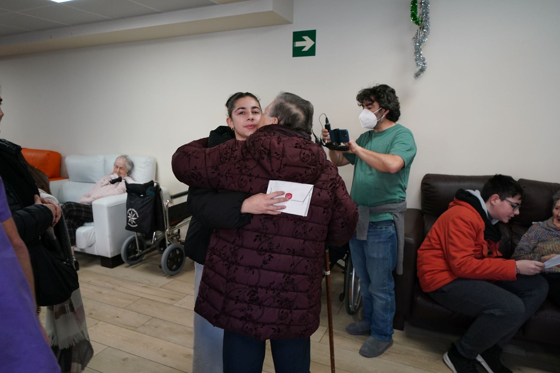 Una alumna y una señora mayor se abrazan después de leer la carta.