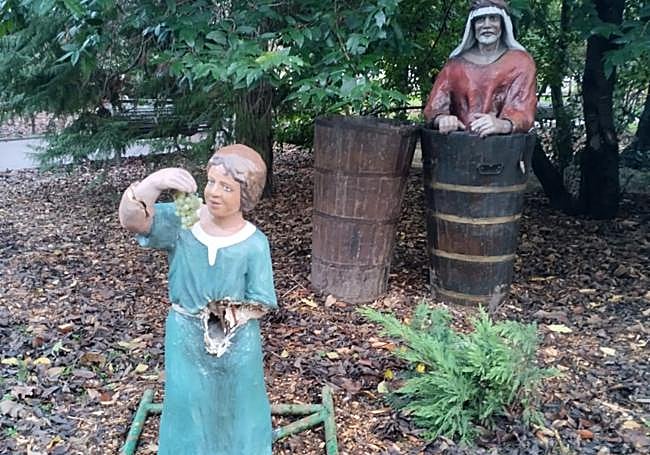 La figura del niño se sitúa junto a un hombre que pisa uvas.