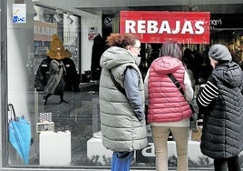 Un grupo de mujeres echa un vistazo a un escaparate del Casco Viejo con un cartel anunciando rebajas.