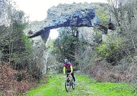 Un ciclista pasa bajo el arco de piedra de Jentilzubi.