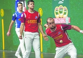 Elordi se agacha para golpear la pelota con la derecha ante la mirada de su compañero en el frontón Ogueta.