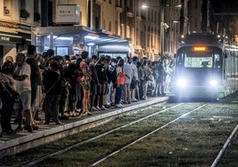 Muchas personas esperan el tranvia nocturno durante las Fiestas de La Blanca.