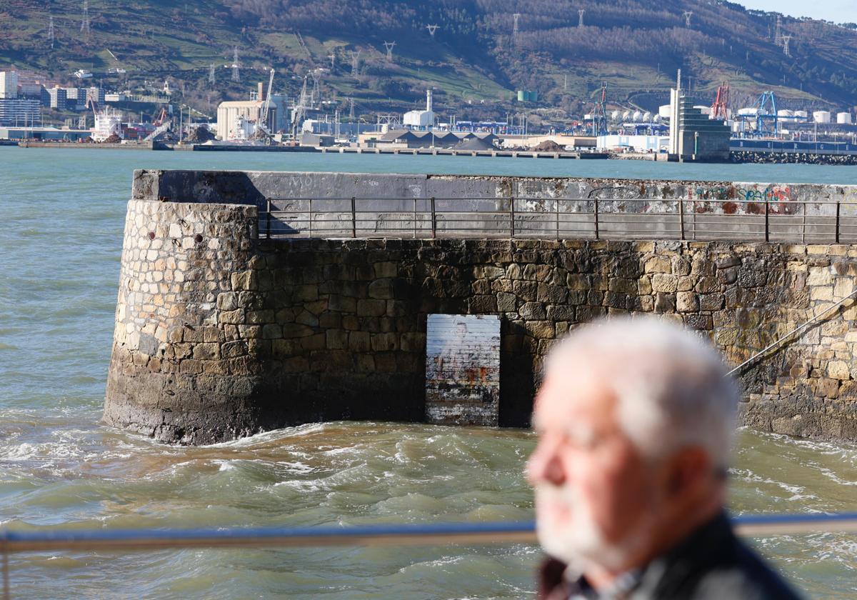 Un vecino de Getxo pasea por el Puerto Viejo de Getxo donde está colocada la obra artística del sireno