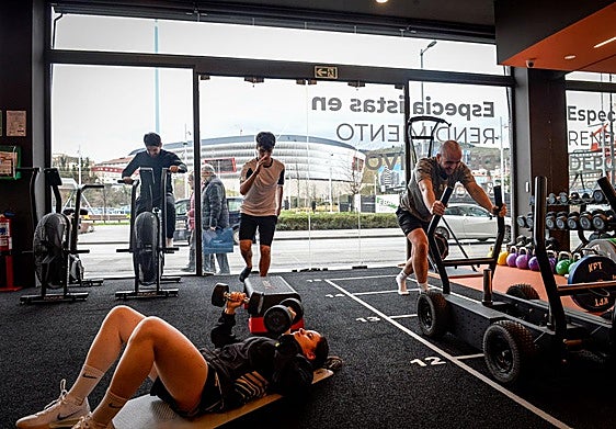 Usuarios se ejercitan en Emen4sport., en Deusto. Al fondo, San Mamés.