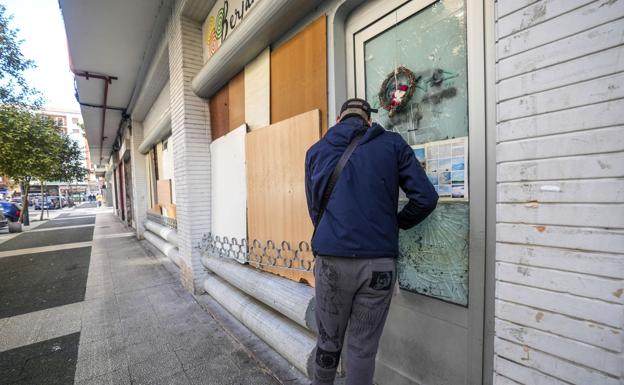 El cabeza de familia retira el candado y la cadena de la puerta principal de la lonja okupada.