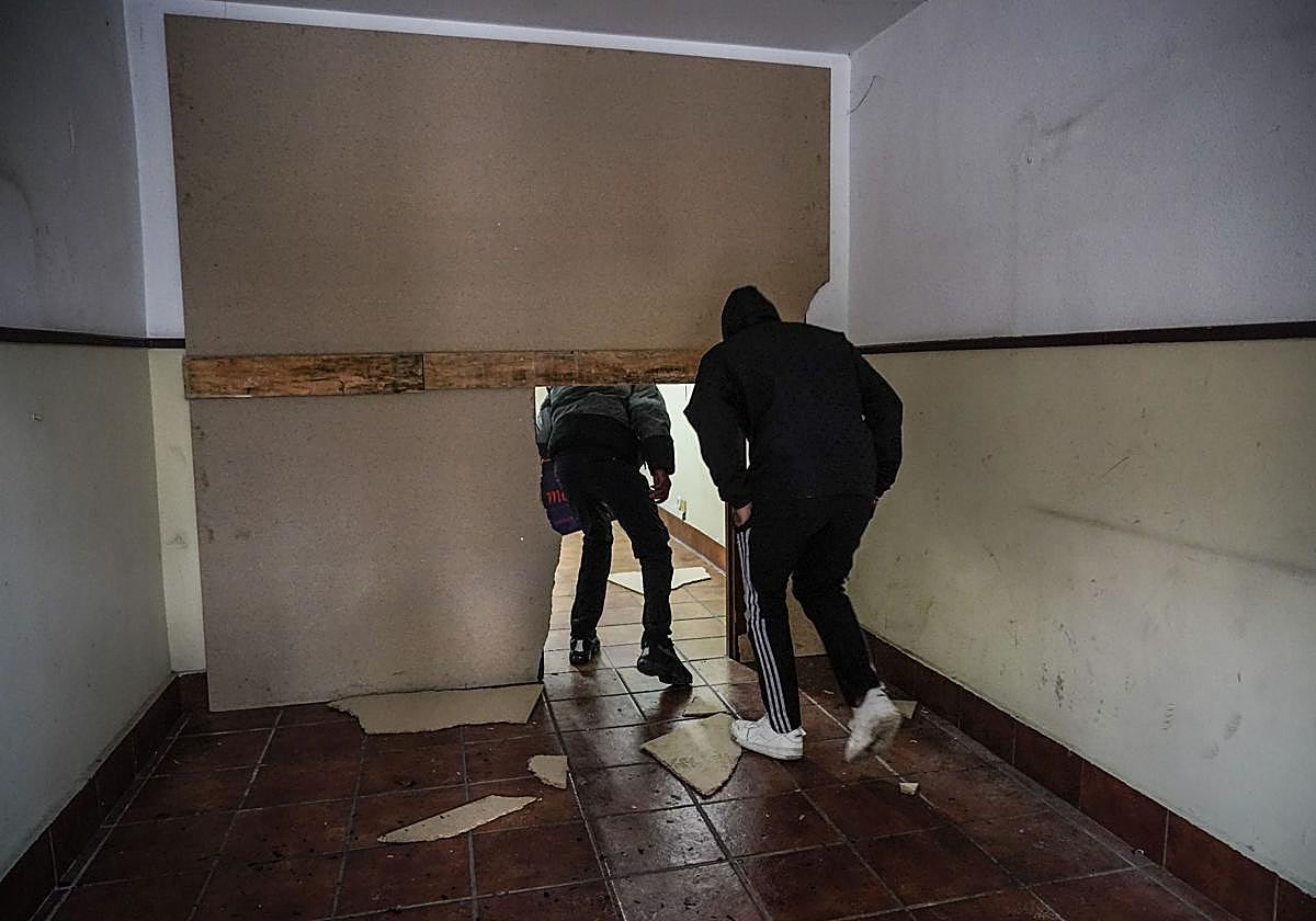 Dos okupas acceden a los pisos por un boquete hecho en el muro de pladur colocado por los Bomberos a modo de tapia.