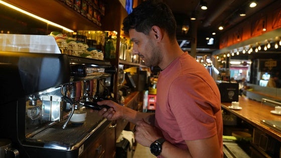 Un hostelero prepara un café con leche en un local de Ledesma.