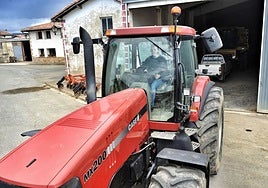 Un joven sale con su tractor de un pabellón agrícola.
