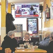 Un grupo de mujeres toma café en un bar mientras en la televisión se emite un programa informativo.