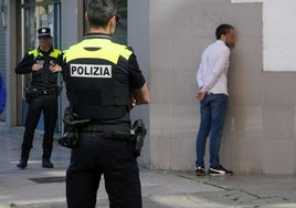 Policías locales custodian a uno de los sospechosos en una calle del barrio de Aranbizkarra.