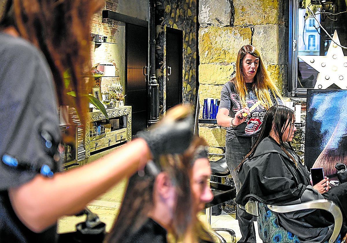 Ainara Cermeño, propietaria de la peluquería Im Miu, en el Ensanche bilbaíno, corta el pelo a una clienta.