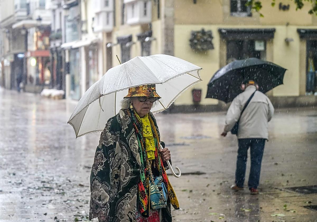 Una mujer se protege de la lluvia en el centro de Vitoria.