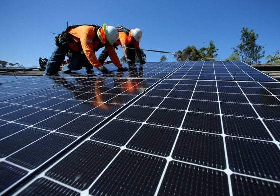 Dos técnicos trabajan en la instalación de paneles solares en una planta de producción fotovoltaica.
