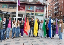 Representantes de grupos políticos y asociaciones despliegan banderas arcoíris en un acto simbólico.