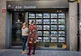 Unas jóvenes se fijan en la oferta de pisos en una inmobiliaria de Bilbao.