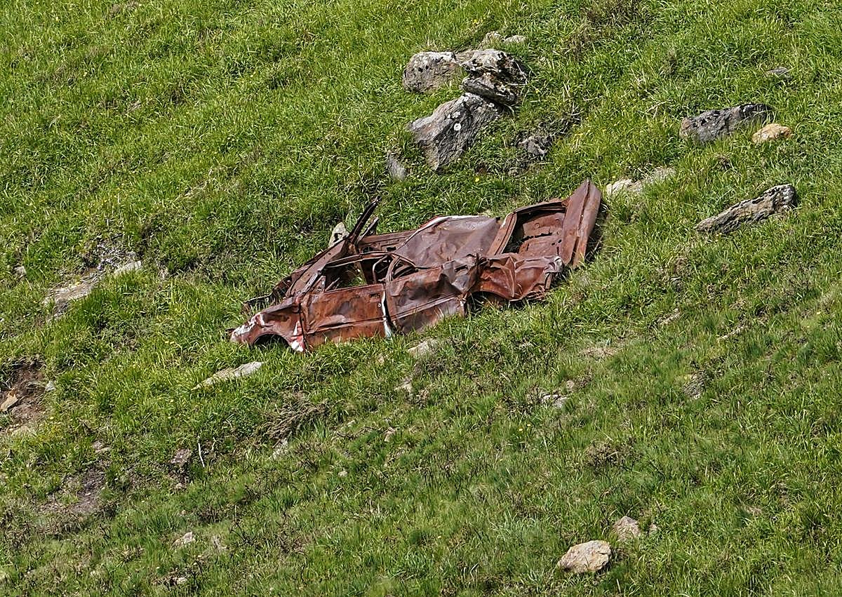 Imagen secundaria 1 - Roberto Ortiz, en el punto de Lunada donde se despeñaron los jóvenes madrileños. Restos del vehículo accidentado en los 90. Cruz hecha con palos en recuerdo del motorista alemán, junto a la señal contra la que se estrelló. 