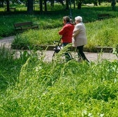 Una mujer y su cuidadora pasean por una zona de jardines asilvestrada